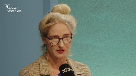 Christine Wahl spricht in ein Mikrofon und gestikuliert mit seiner linken Hand