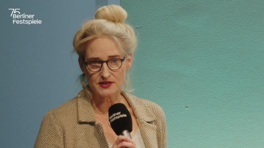 Christine Wahl spricht in ein Mikrofon und gestikuliert mit seiner linken Hand