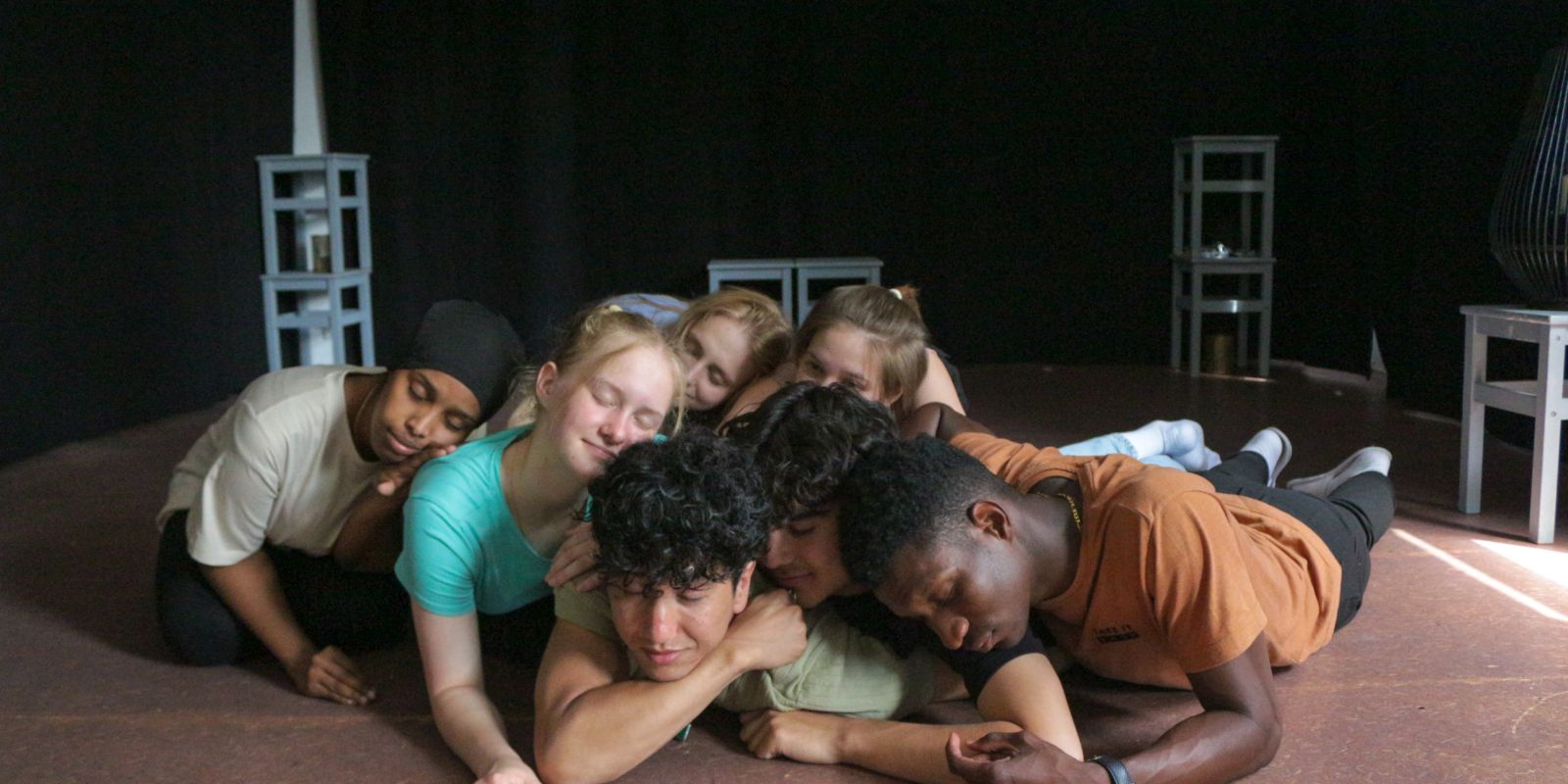 Sieben Personen liegen auf dem Bühnenboden. Sie haben die Augen geschlossen und sind innig, vertraut und nah.