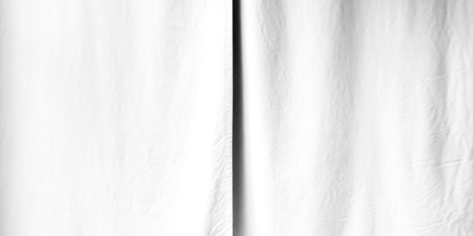 Black-and-white image of a closed white curtain.