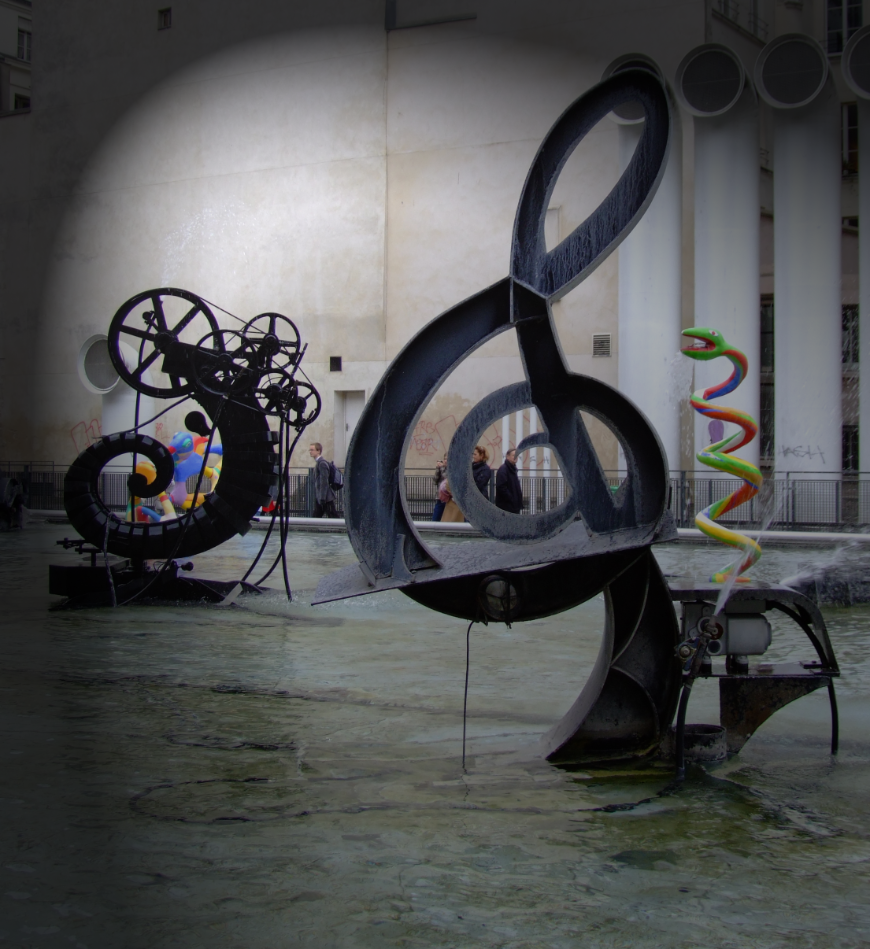 View of the Strawinsky Fountain with sculptures by Niki de Saint Phalle and Jean Tinguely. 
They form a contrast with their rather mechanical, iron constructions and colorful, physical forms. One of the sculptures is shaped like a clef.